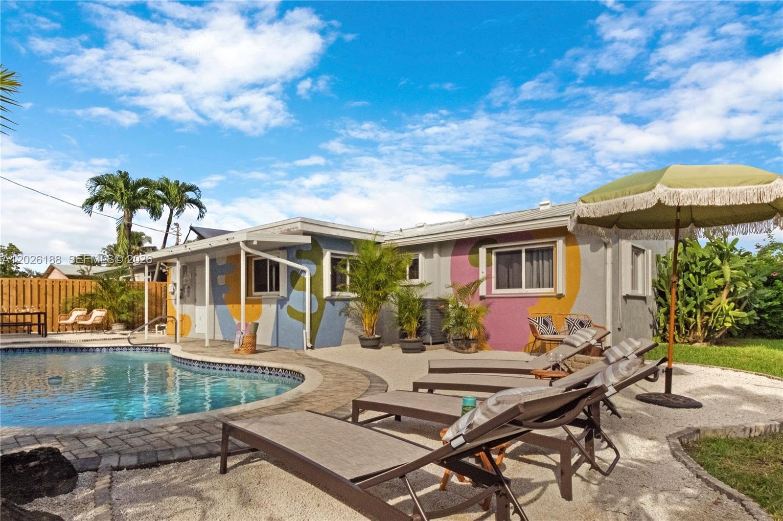 A backyard features a swimming pool, lounge chairs, and a house with colorful painted walls — 191 SE 13th Ave, Pompano Beach FL 33060, POMPANO BEACH, FL