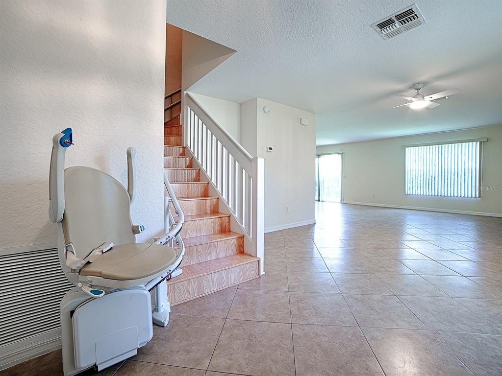 An interior view shows a staircase with a chair lift and an adjacent tiled living area — 12319 NE 52ND LOOP, OXFORD, FL