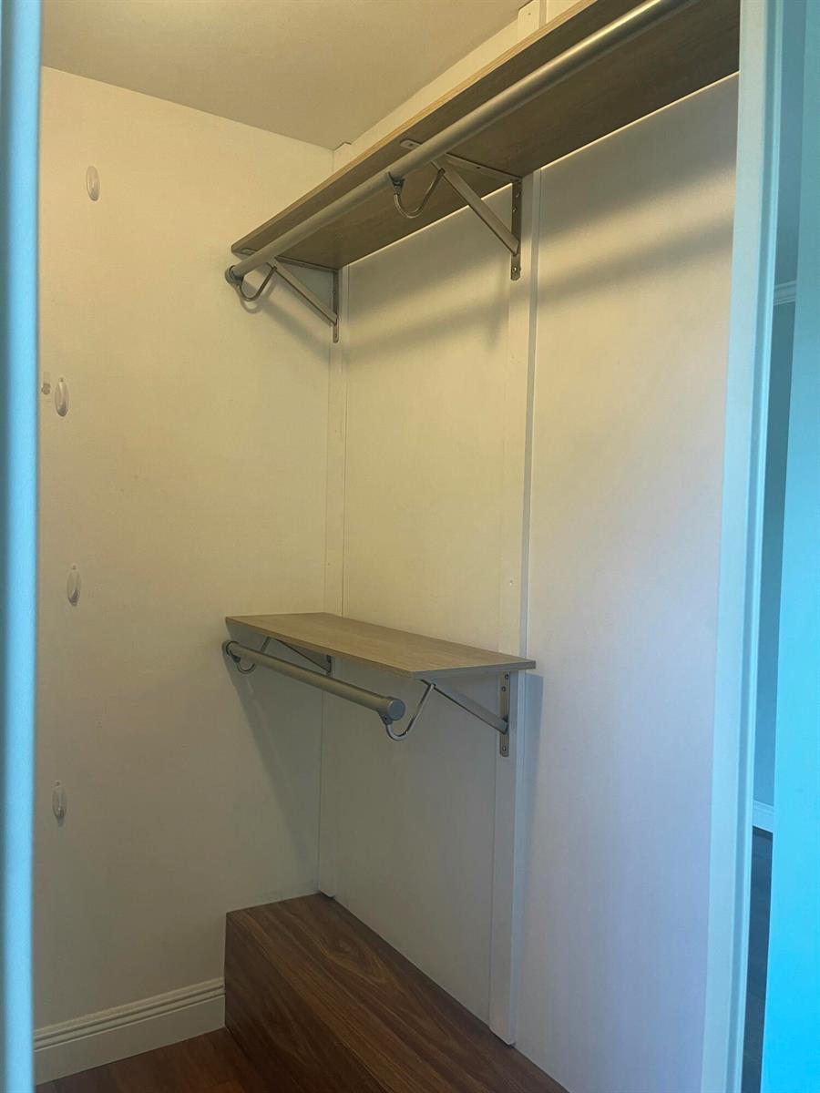 A walk-in closet features two levels of shelving with hanging rods and wood-look flooring — 1612 16th Court, Jupiter FL 33477, JUPITER, FL