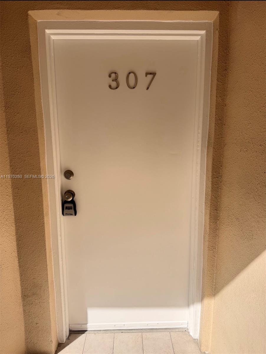 A white door labeled 307 with a lockbox is set into a tan stucco wall — 8050 NW 8th St # 1307, Miami FL 33126, MIAMI, FL
