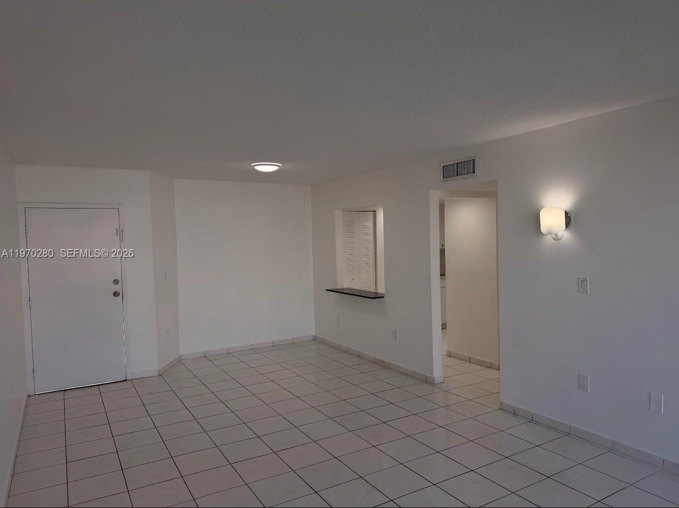 An empty room with white walls, white tile flooring, a doorway, and a pass-through window — 8050 NW 8th St # 1307, Miami FL 33126, MIAMI, FL