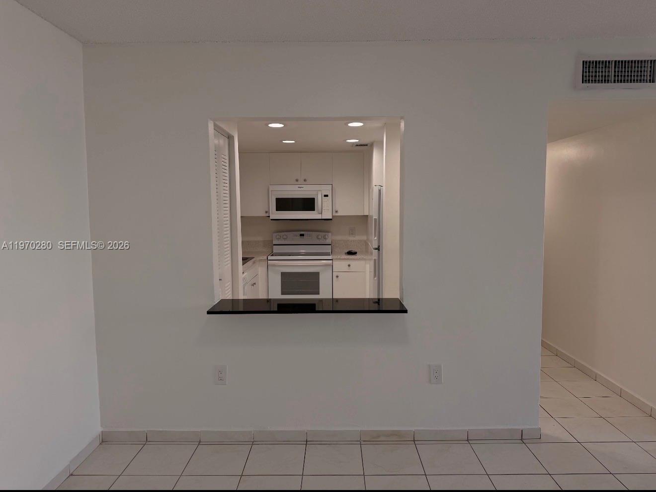 A kitchen with white cabinets and appliances is visible through a pass-through window — 8050 NW 8th St # 1307, Miami FL 33126, MIAMI, FL