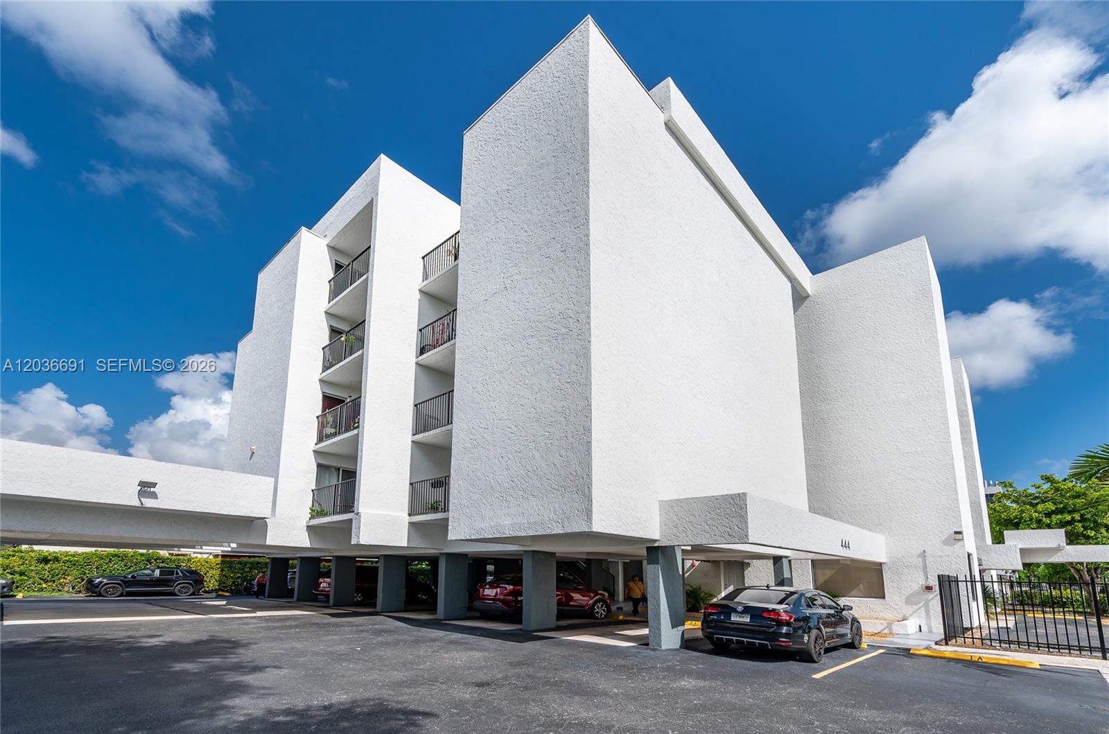 A multi-story white apartment building features covered ground-level parking and stacked balconies — 444 SW 27th Ave # 50, Miami FL 33135, MIAMI, FL