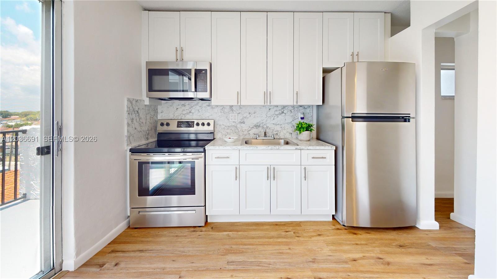 A kitchen features white cabinetry, stainless steel appliances, and a marble-patterned backsplash — 444 SW 27th Ave # 50, Miami FL 33135, MIAMI, FL