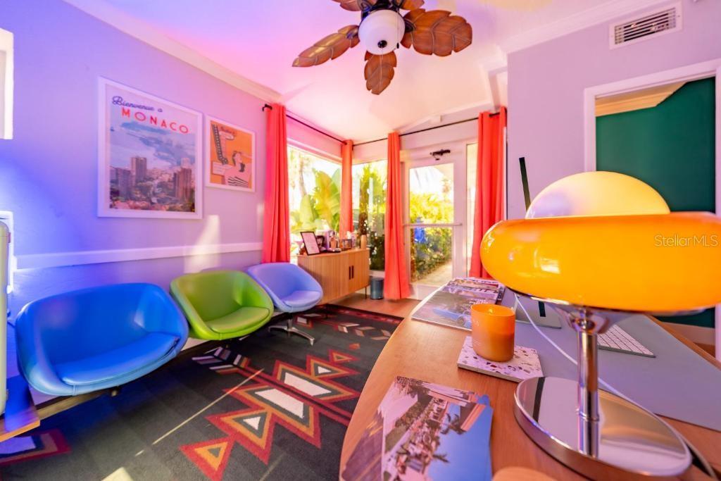 A colorful office features a desk with a yellow lamp, three chairs, and patterned carpeting — 648 POINSETTIA AVENUE, CLEARWATER BEACH, FL