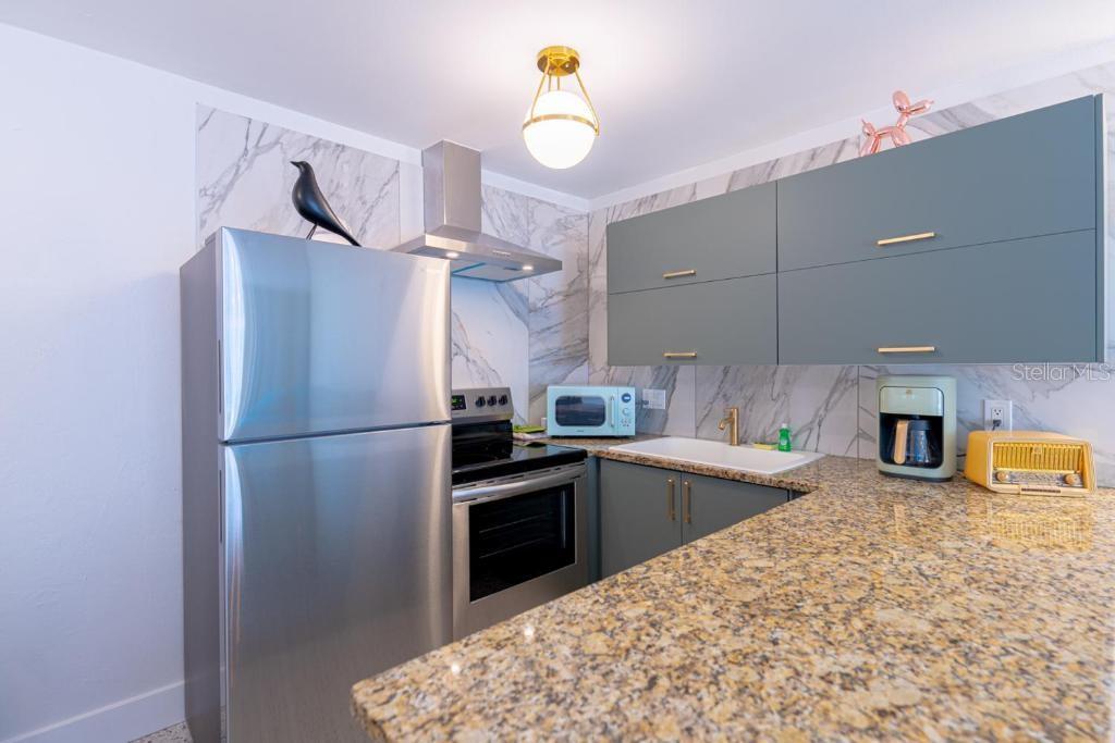 A kitchen features stainless steel appliances, gray cabinets, and a granite countertop — 648 POINSETTIA AVENUE, CLEARWATER BEACH, FL