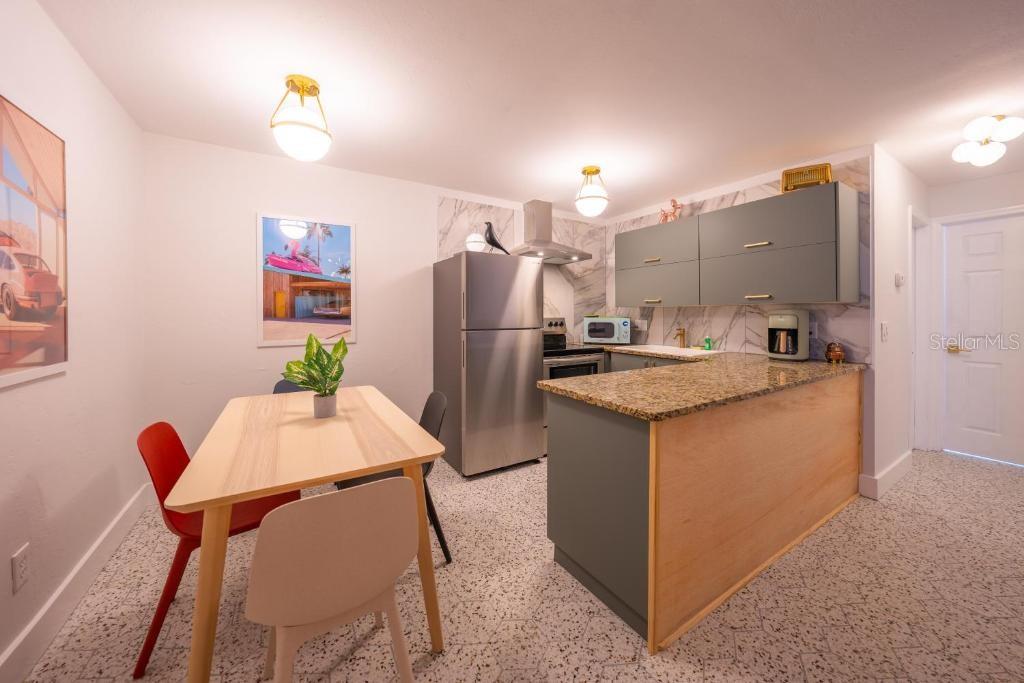 A kitchen and dining area with gray cabinets, granite countertops, and a light wood table — 648 POINSETTIA AVENUE, CLEARWATER BEACH, FL