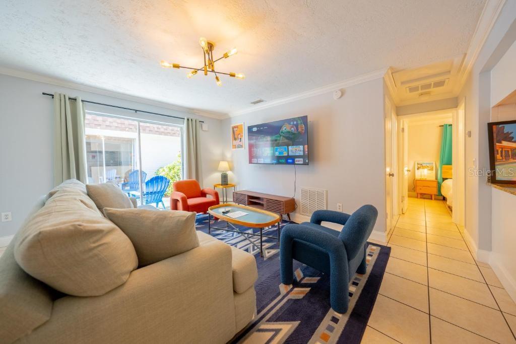 A living room with a sofa, two armchairs, a television, and a sliding glass door — 648 POINSETTIA AVENUE, CLEARWATER BEACH, FL
