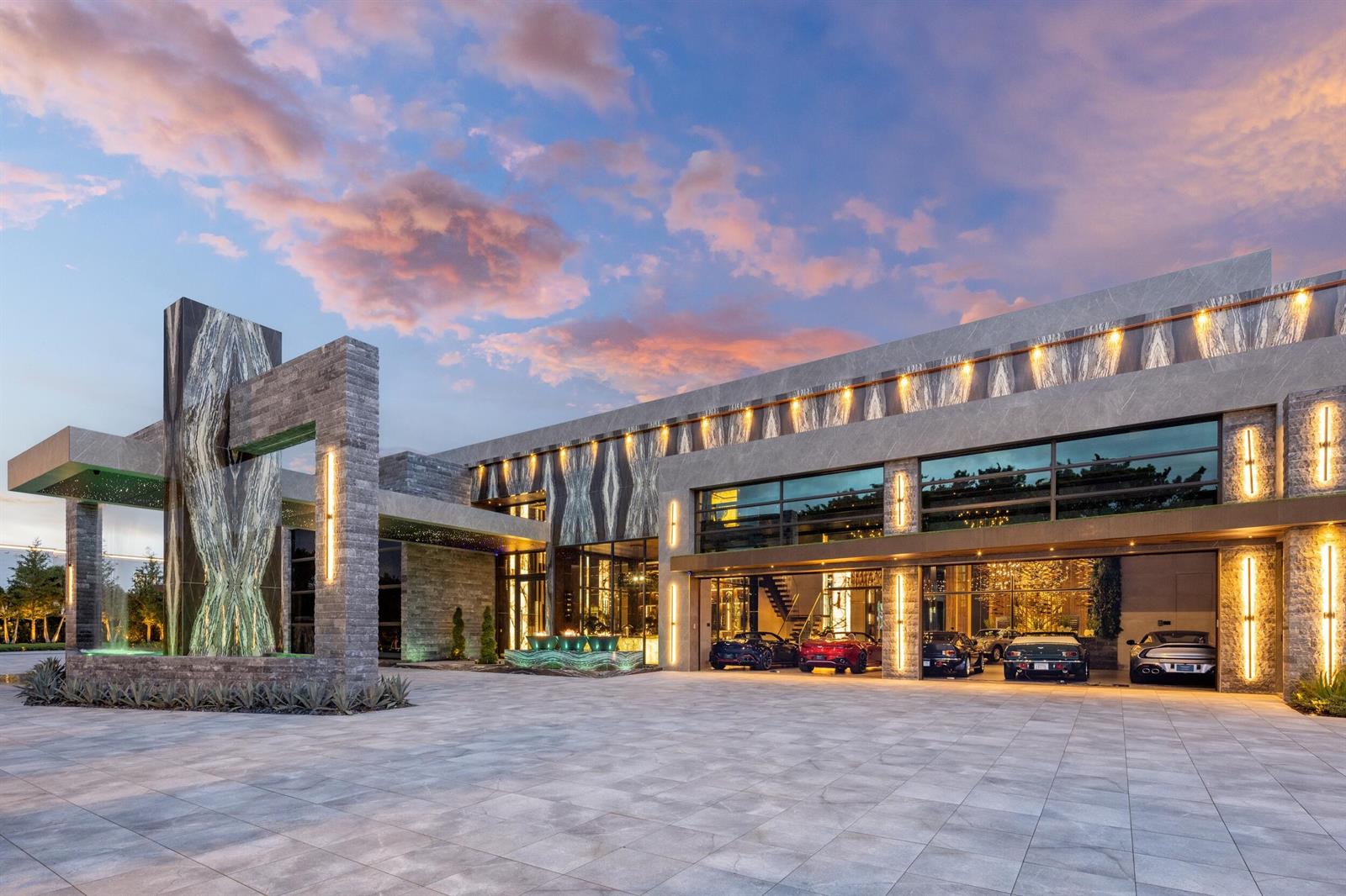 A modern luxury home exterior features stone cladding, a large garage, and a fountain — 16121 Quiet Vista Circle, Delray Beach FL 33446, DELRAY BEACH, FL