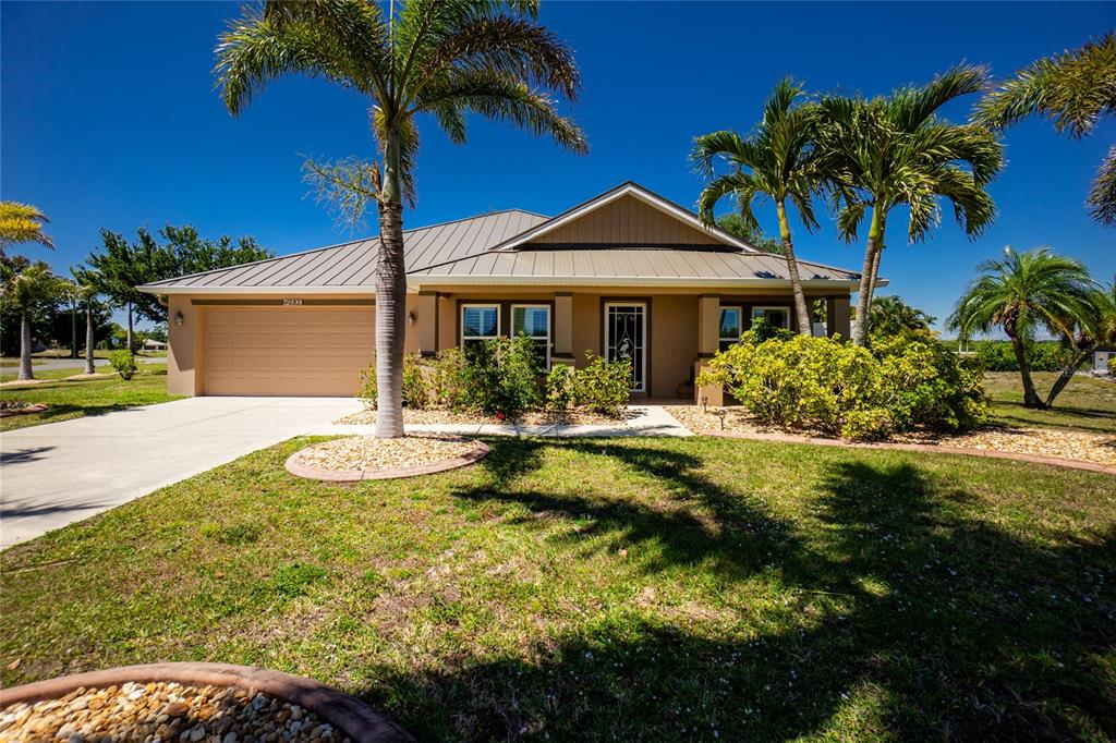A single-story house with a metal roof, a two-car garage, and palm trees in front — 17200 NILE CT, PUNTA GORDA, FL