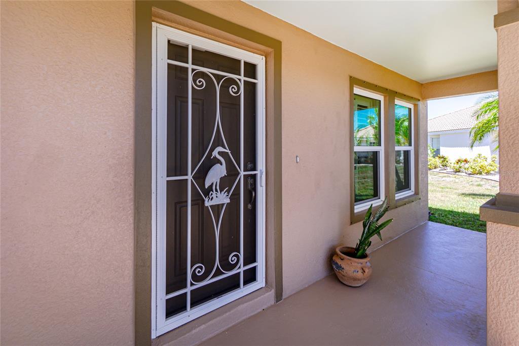 A white decorative screen door with a heron design sits on a tan covered porch — 17200 NILE CT, PUNTA GORDA, FL