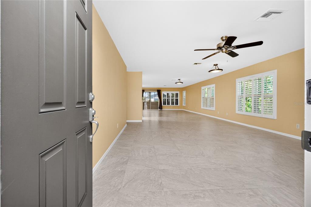 An open-concept living area features light-colored tile flooring, tan walls, and a ceiling fan — 17200 NILE CT, PUNTA GORDA, FL