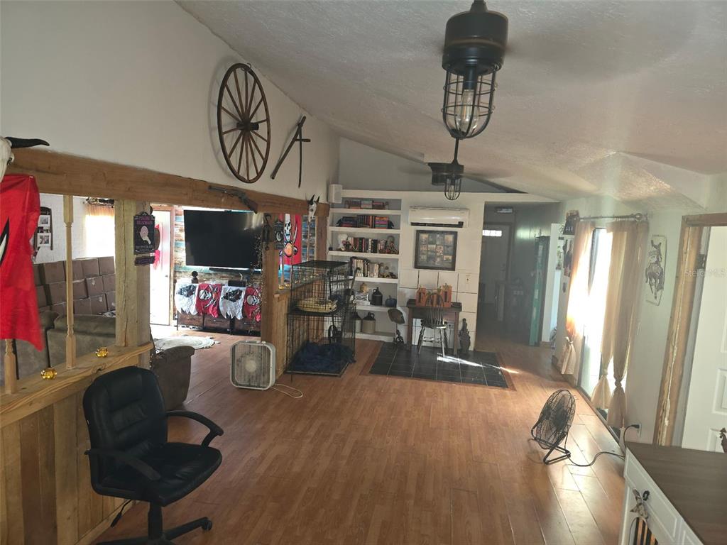 A living room features wood-look flooring, a ceiling fan, built-in shelving, and a wooden beam — 12510 ROBINHOOD ROAD, HUDSON, FL