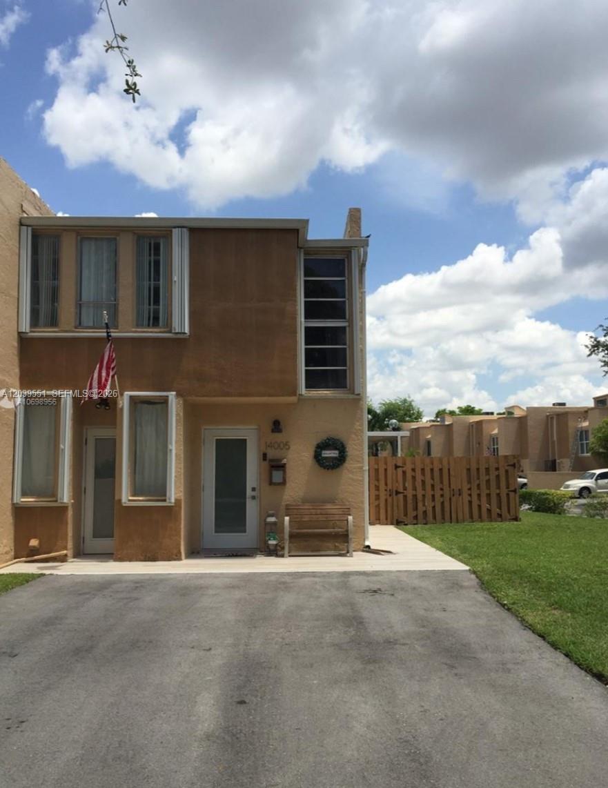 A two-story tan stucco townhouse features a paved driveway and a wooden privacy fence — 14005 SW 67th Ter, Miami FL 33183, MIAMI, FL