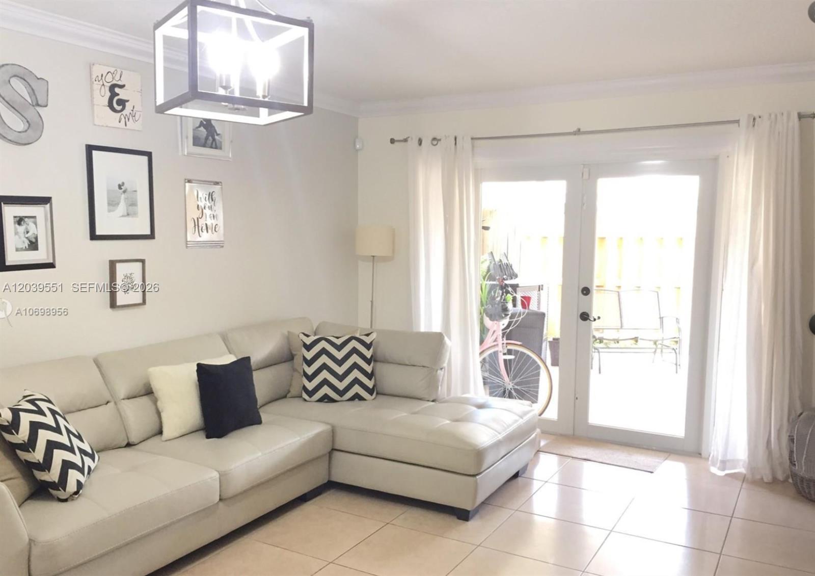 A living room features a light-colored sectional sofa, a modern chandelier, and glass patio doors — 14005 SW 67th Ter, Miami FL 33183, MIAMI, FL