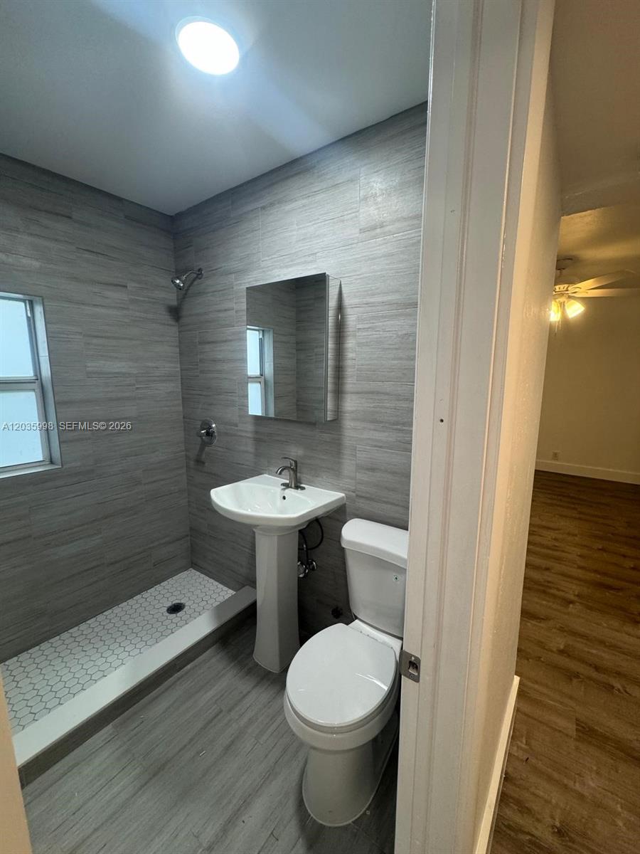 A small bathroom features gray tile walls, a pedestal sink, and a walk-in shower — 350 SW 15th Rd # 9, Miami FL 33129, MIAMI, FL