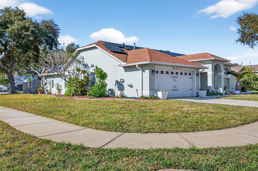 A single-story house with a white garage, solar panels on the roof, and landscaped yard — 5102 COCOPLUM AVENUE, MELBOURNE, FL