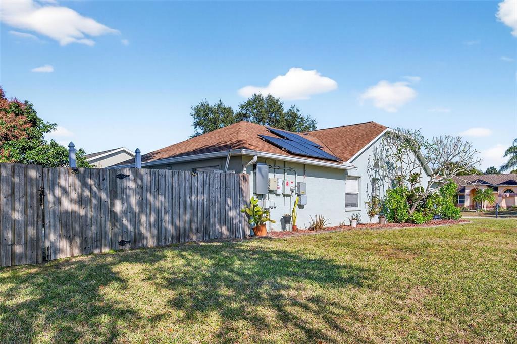 The exterior of a house features a wooden fence, solar panels, and electrical equipment — 5102 COCOPLUM AVENUE, MELBOURNE, FL