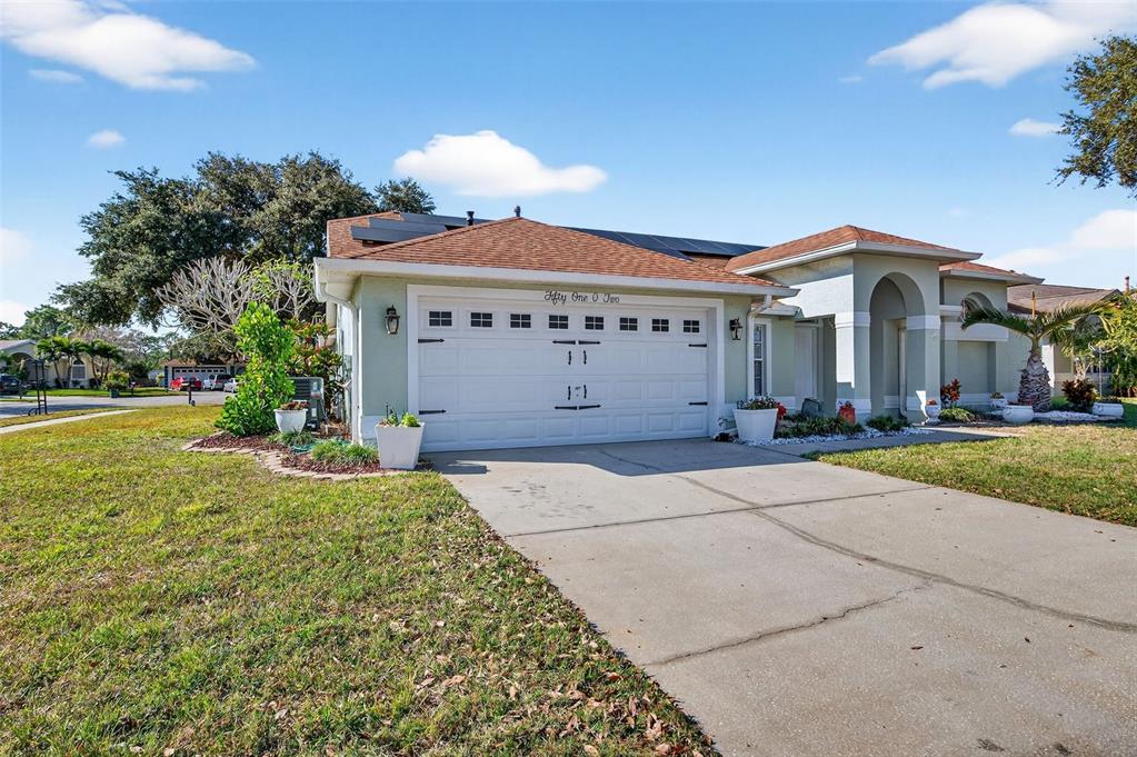 A single-story house with a white garage door, light green siding, and solar roof panels — 5102 COCOPLUM AVENUE, MELBOURNE, FL