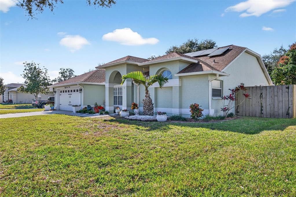 A single-story house with a light green exterior, a two-car garage, and a wooden fence — 5102 COCOPLUM AVENUE, MELBOURNE, FL