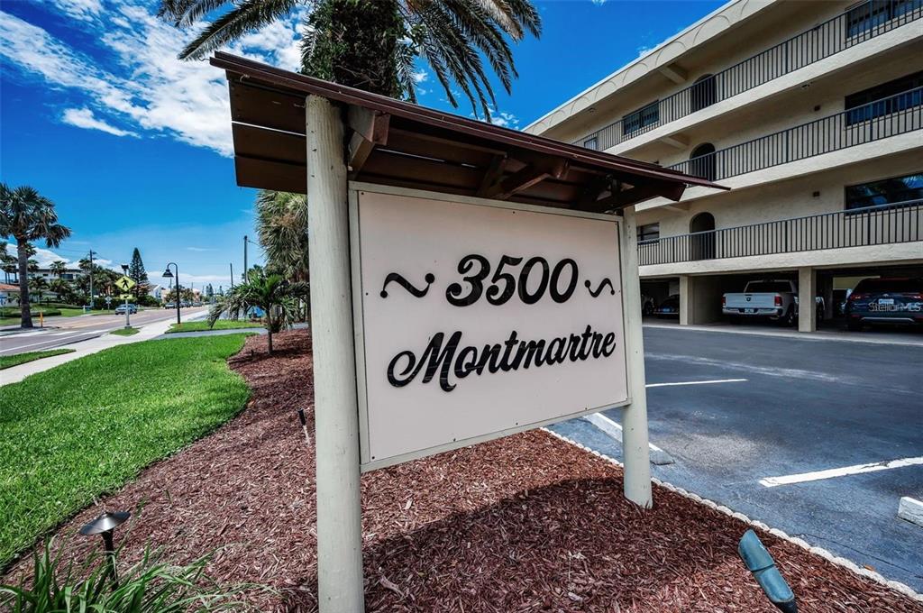 A sign for a residential building stands in front of a multi-story apartment complex — 3500 GULF BOULEVARD UNIT 407B, BELLEAIR BEACH, FL