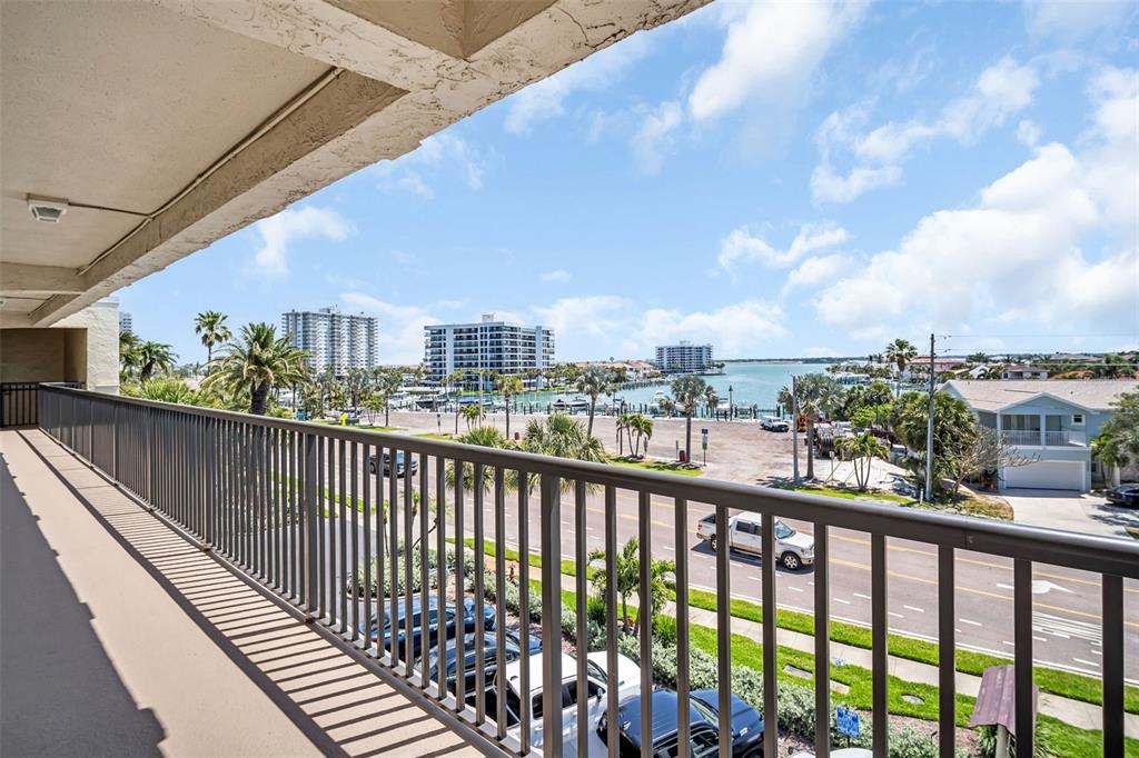 A view from a balcony overlooking a street, parking area, and a body of water — 3500 GULF BOULEVARD UNIT 407B, BELLEAIR BEACH, FL