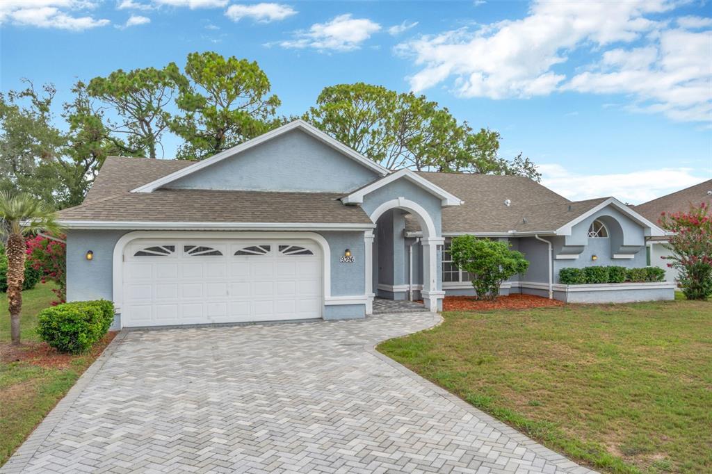 A single-story house with a blue stucco exterior, a paved driveway, and a two-car garage — 9396 SOUTHERN BELLE DRIVE, BROOKSVILLE, FL