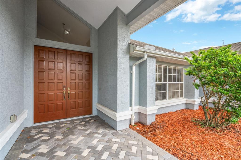 A front entryway features double wooden doors, a brick paver porch, and a small tree — 9396 SOUTHERN BELLE DRIVE, BROOKSVILLE, FL