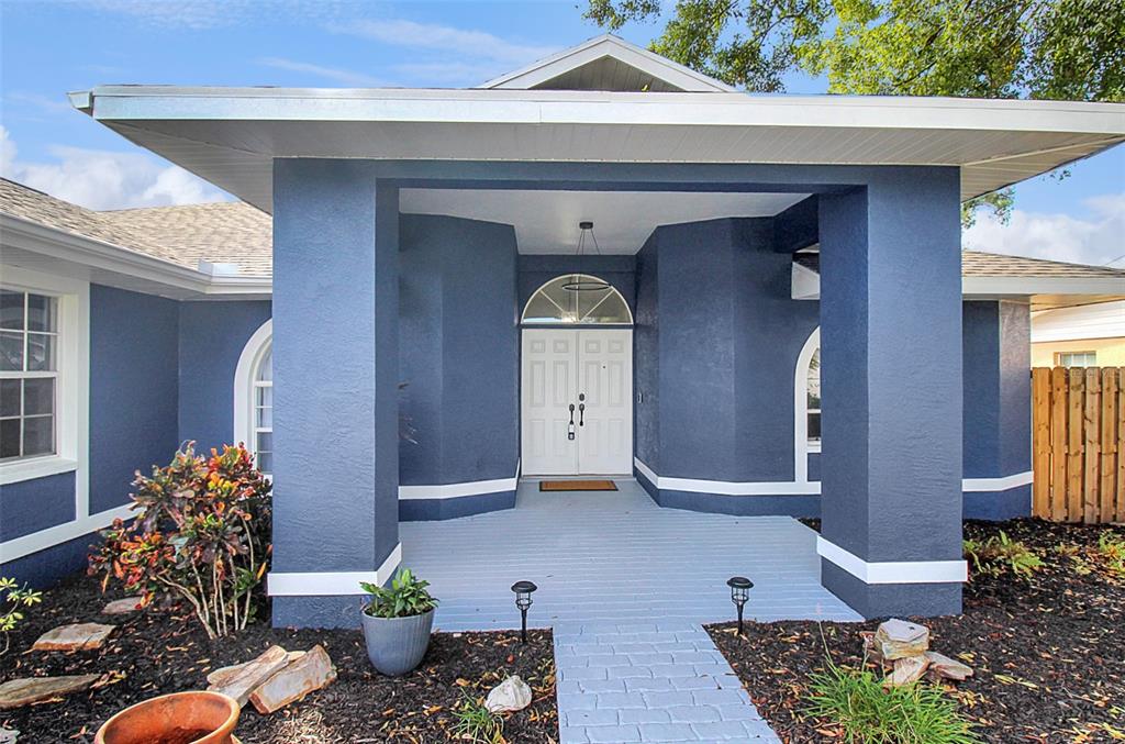 The exterior of a blue house features a covered front porch with white double doors — 5111 13TH AVENUE DRIVE W, BRADENTON, FL