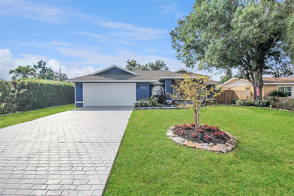 A blue single-story house with a paved driveway and a landscaped front yard — 5111 13TH AVENUE DRIVE W, BRADENTON, FL