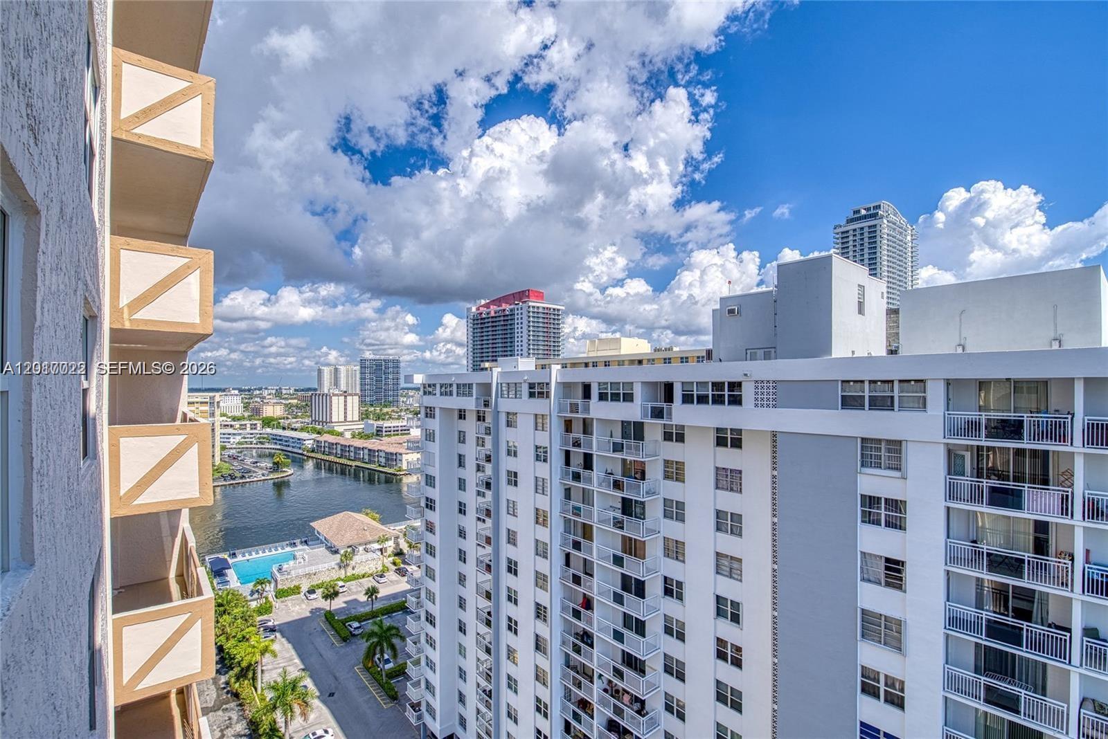An elevated view shows a canal, swimming pool, and surrounding high-rise apartment buildings under clouds — 1865 S Ocean Dr # 15C, Hallandale Beach FL 33009, HALLANDALE BEACH, FL
