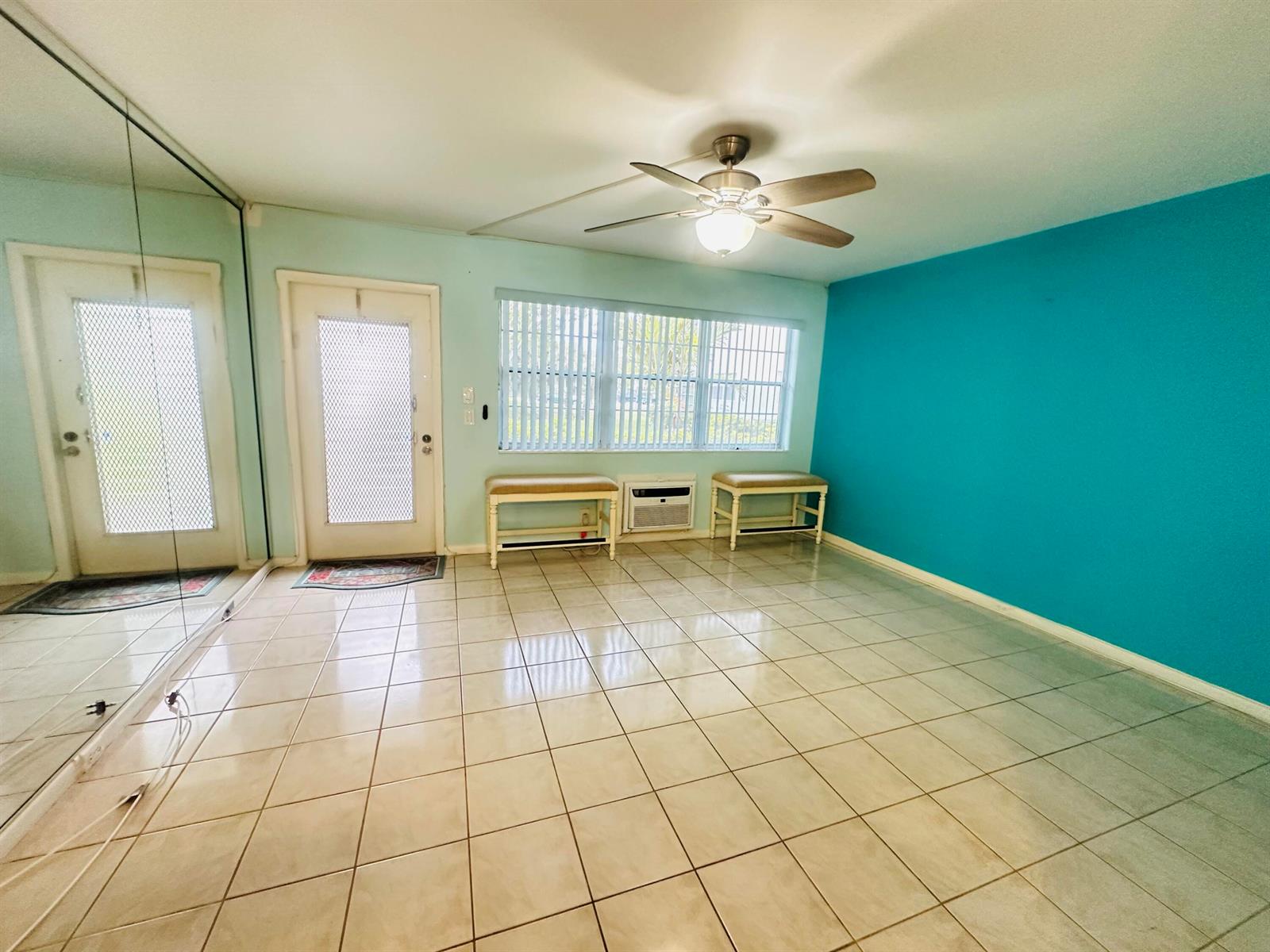 A room with light-colored tile flooring, a ceiling fan, and a bright blue accent wall — 86 Markham E, Deerfield Beach FL 33442, DEERFIELD BEACH, FL