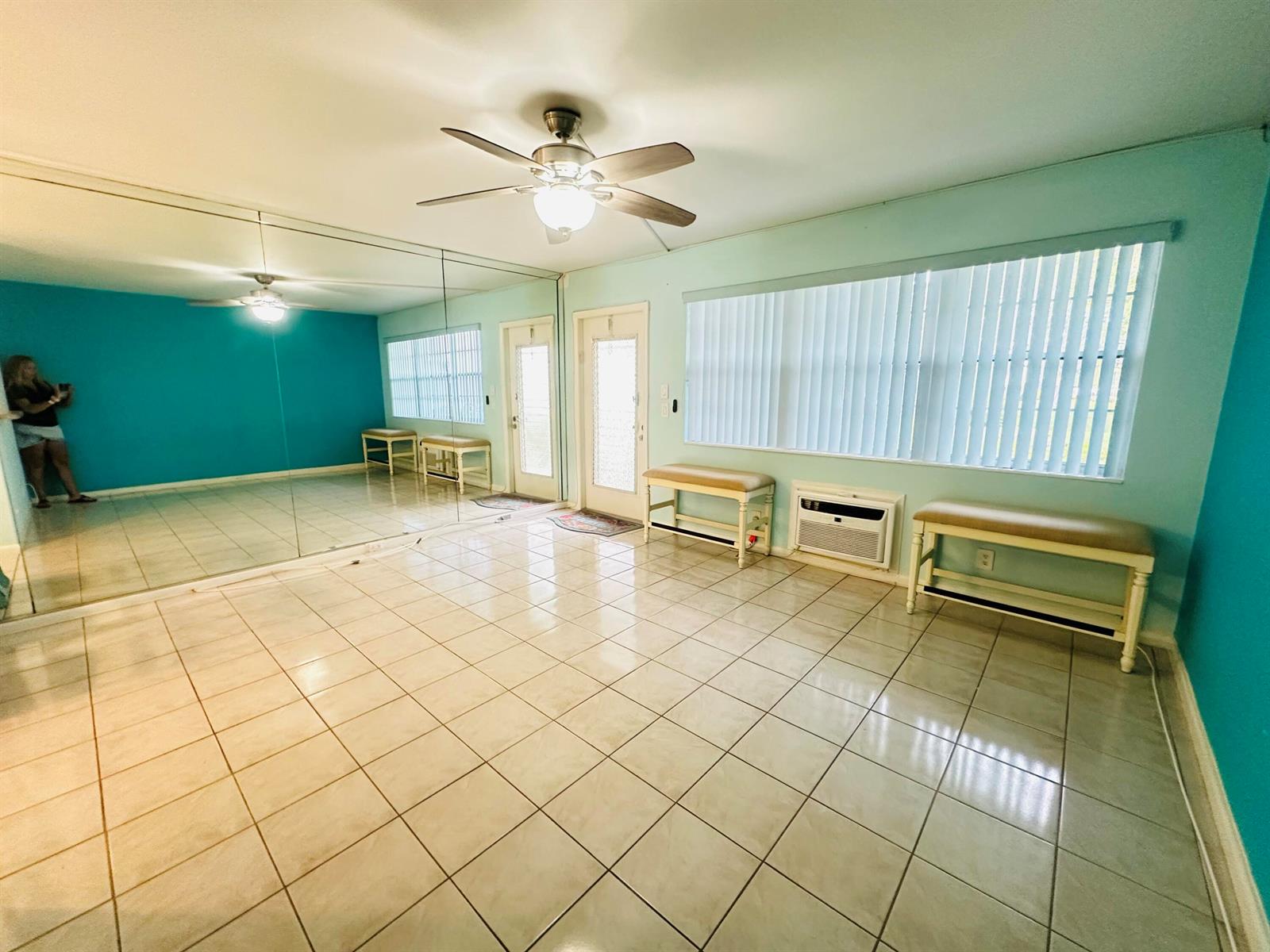 A room with tiled floors, mirrored walls, a ceiling fan, and two benches under windows — 86 Markham E, Deerfield Beach FL 33442, DEERFIELD BEACH, FL