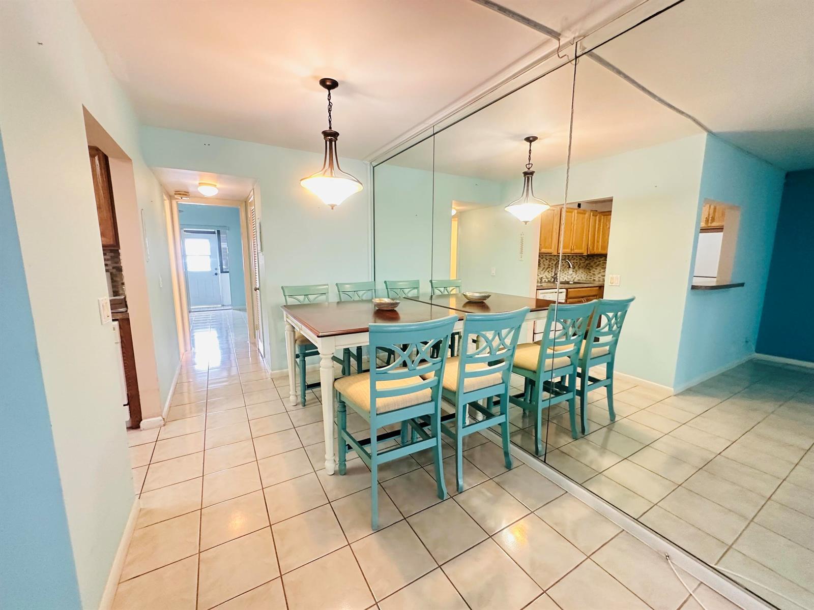 A dining area features a wooden table, blue chairs, and a large mirrored wall — 86 Markham E, Deerfield Beach FL 33442, DEERFIELD BEACH, FL