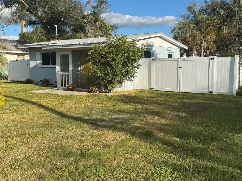 A light blue house with a screened porch and white vinyl fencing in the yard — 525 SHOWALTER AVENUE, PUNTA GORDA, FL