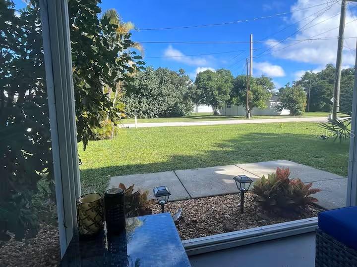 A view from a screened-in porch looking out onto a grassy yard and trees — 525 SHOWALTER AVENUE, PUNTA GORDA, FL
