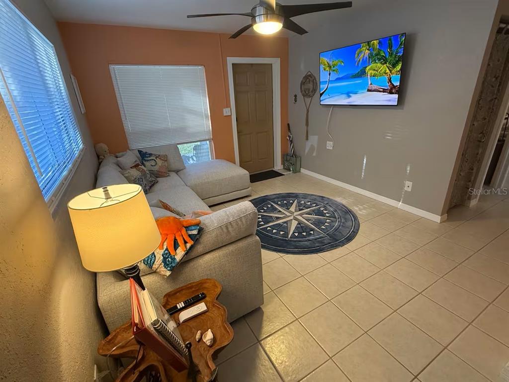 A living room features a sectional sofa, a wall-mounted television, and a circular area rug — 525 SHOWALTER AVENUE, PUNTA GORDA, FL