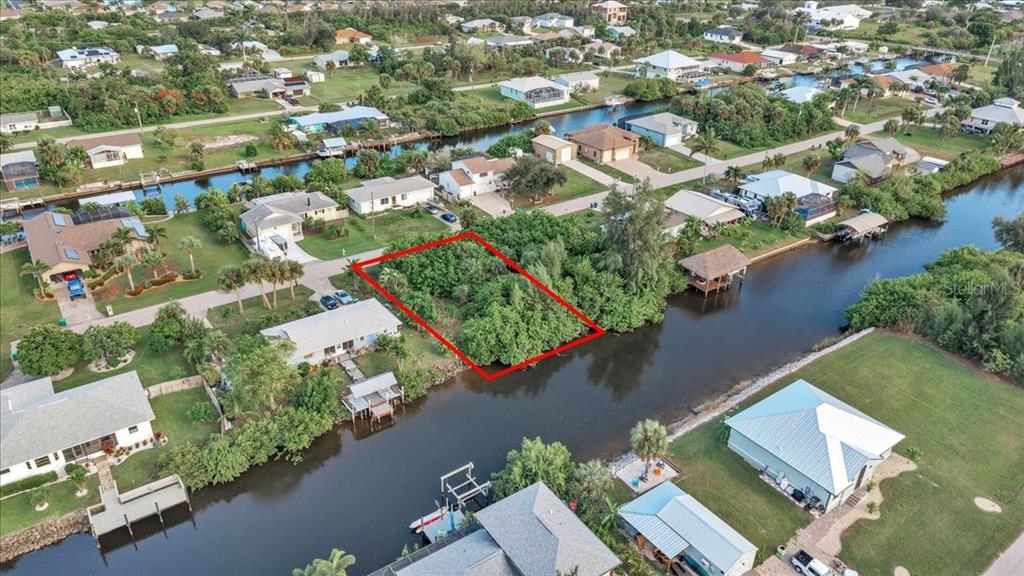 An aerial view shows a vacant, tree-covered waterfront lot outlined in red — 3623 MAGNOLIA WAY, PUNTA GORDA, FL