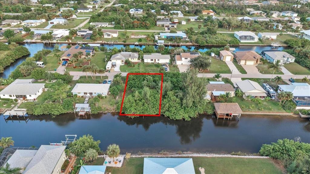 An aerial view shows a vacant, tree-covered waterfront lot outlined in red — 3623 MAGNOLIA WAY, PUNTA GORDA, FL