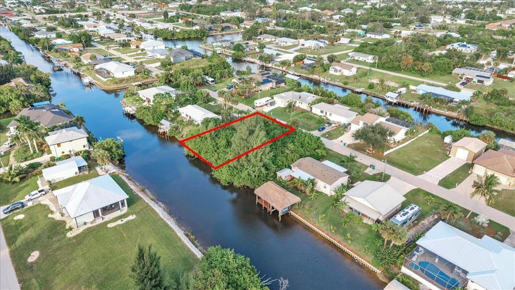 An aerial view shows a vacant, tree-covered waterfront lot outlined in red — 3623 MAGNOLIA WAY, PUNTA GORDA, FL