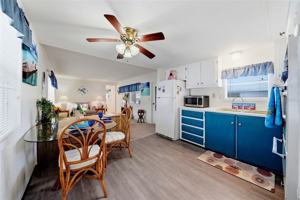 A kitchen and dining area with blue cabinets, a glass table, and a ceiling fan — 12116 HORSESHOE LANE, HUDSON, FL