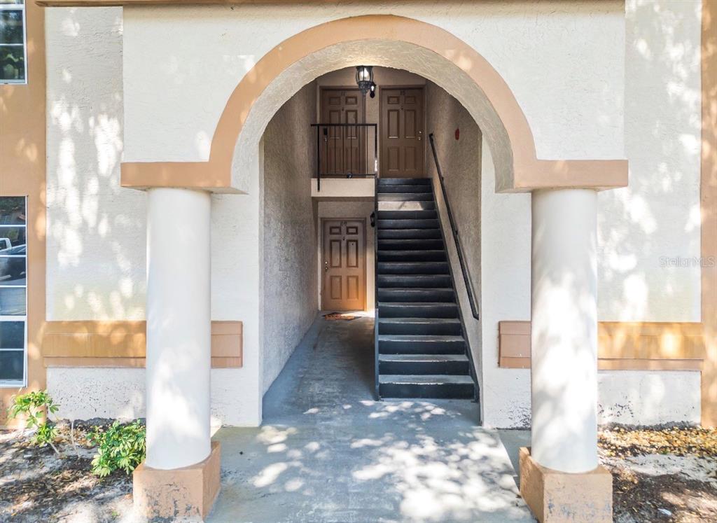 An exterior view shows a covered entryway with stairs leading to two upper-level doors — 4613 GATE PLACE UNIT 104, ORLANDO, FL