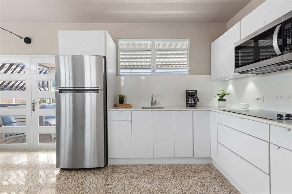 A modern kitchen features white cabinets, stainless steel appliances, and a speckled stone floor — 56 MARÍA MOCZO UNIT 2, SAN JUAN, PR