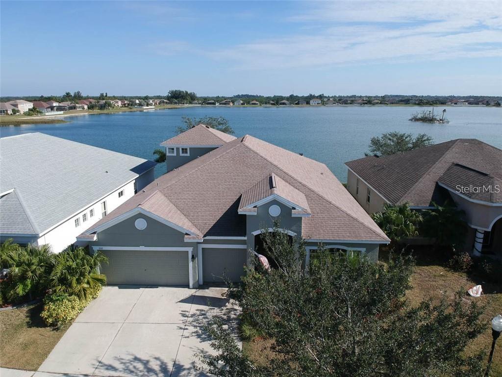 An aerial view of a suburban house with a garage facing a large lake — 1742 MIRA LAGO CIRCLE, RUSKIN, FL