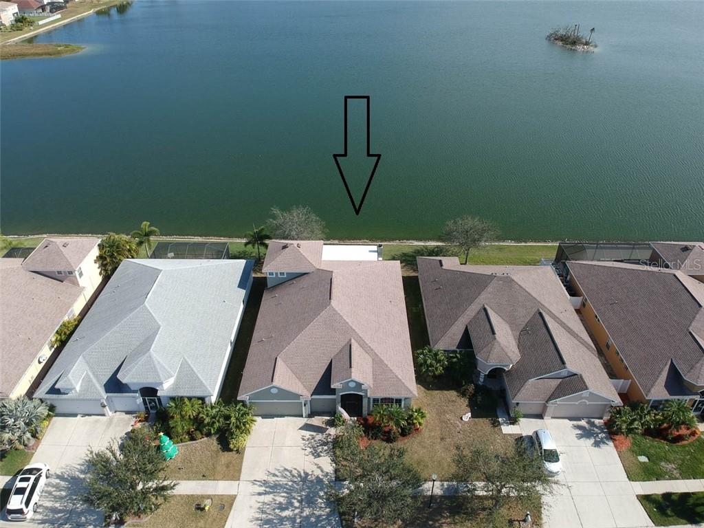 An aerial view shows a suburban house with a backyard patio overlooking a lake — 1742 MIRA LAGO CIRCLE, RUSKIN, FL