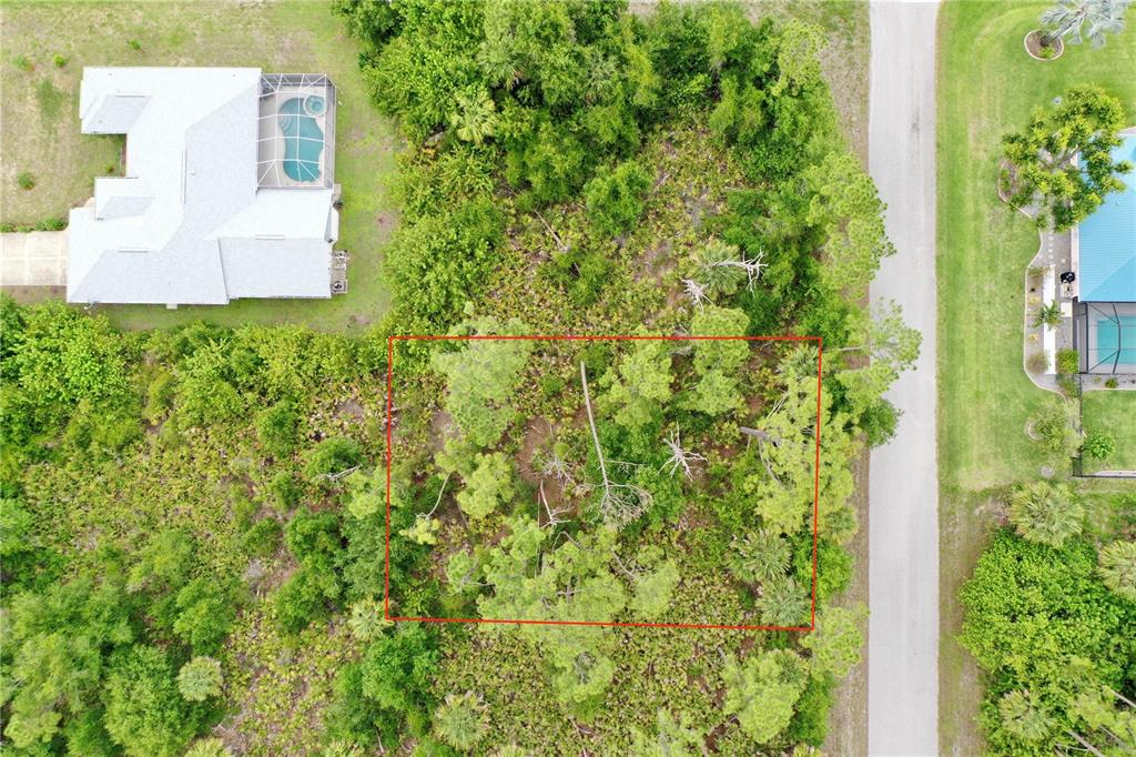 An aerial view shows a rectangular, wooded vacant lot outlined in red next to houses — 3019 SUDBURY STREET, PORT CHARLOTTE, FL