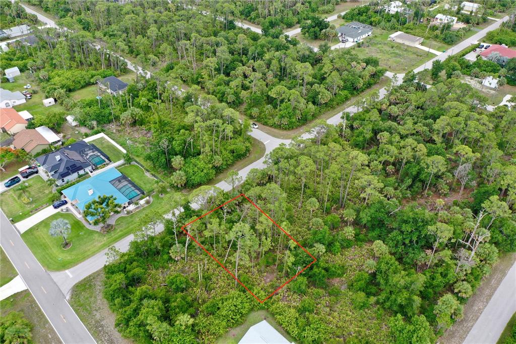 An aerial view shows a vacant, wooded residential lot outlined in red — 3019 SUDBURY STREET, PORT CHARLOTTE, FL