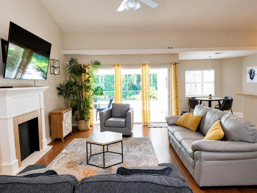 A living room features a fireplace, gray sofa, armchair, and sliding glass doors to a patio — 4394 GLORDANO AVENUE, NORTH PORT, FL