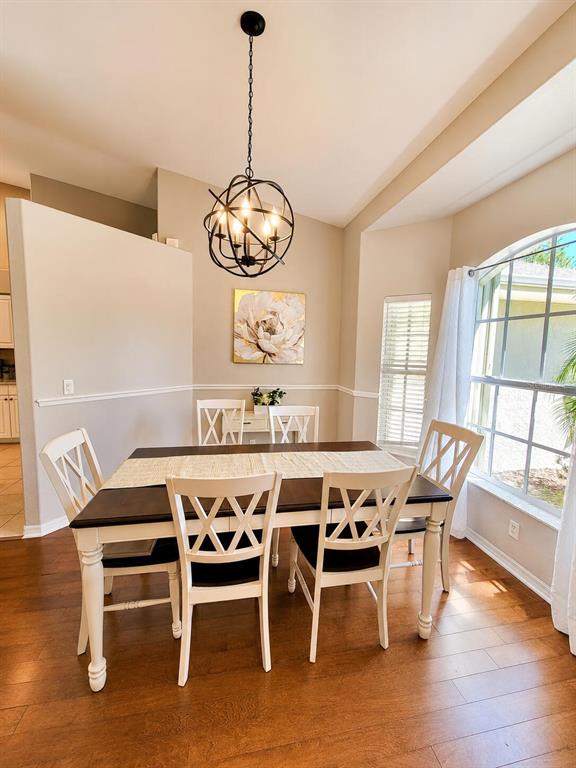 A dining room features a dark wood table, white chairs, and a spherical metal chandelier — 4394 GLORDANO AVENUE, NORTH PORT, FL