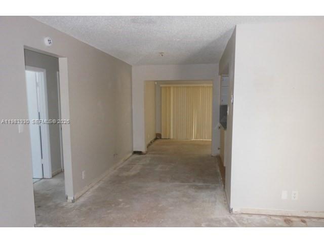 An empty room with beige walls, a textured ceiling, and bare concrete flooring — 7540 Margate Blvd, Margate FL 33063, MARGATE, FL